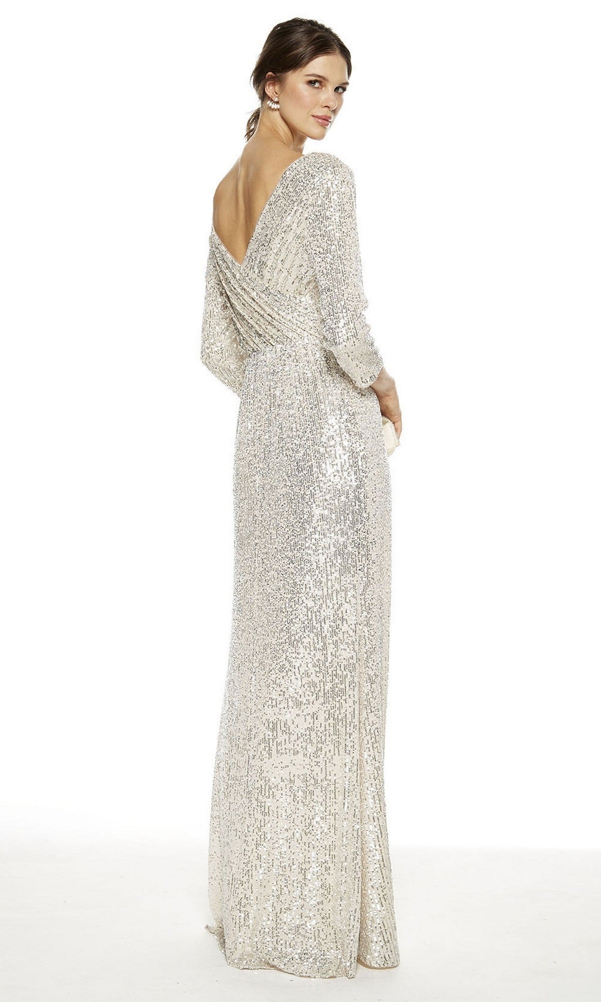 A woman faces backward in the Alyce 27358, a floor-length silver sequin dress with long sleeves and a draped low back—an elegant mother of the bride choice.